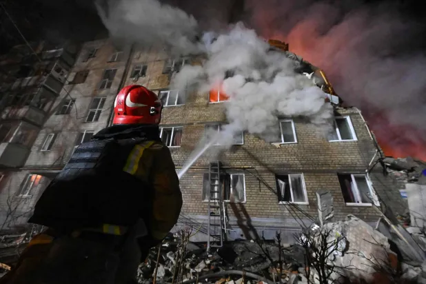 A firefighter extinguishes a blaze at a five-story residential building in Kharkiv on March 7, 2026, after it was partially destroyed by a Russian strike amid the Russian invasion of Ukraine. (Photo by SERGEY BOBOK / AFP)