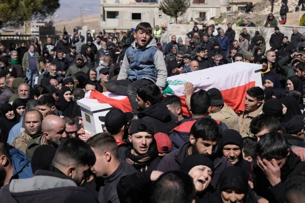 The son of a Lebanese soldier, cries as he sits on his father's coffin who was killed by Israeli airstrikes, during a funeral procession in Khraibeh village, eastern Lebanon, Sunday, March 8, 2026. (AP Photo/Bilal Hussein)
