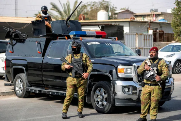 Iraqi security forces stand guard during a funerary procession for a slain member of Iraq's Hashed al-Shaabi, or the Popular Mobilization Forces (PMF) -- an alliance of factions now integrated into the regular army that also includes powerful Iran-backed groups -- who was killed in a US-Israeli air strike in Mosul the previous evening, in Baghdad on March 8, 2026. (Photo by AHMAD AL-RUBAYE / AFP)