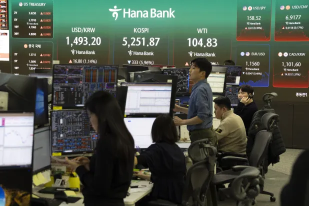 يعمل متداولون كوريون جنوبيون أمام شاشات تعرض مؤشرات الأسهم في بنك هانا بسيول (إ.ب.أ)