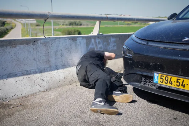 مواطن يتفادي بينما يدوي صوت صافرات الإنذار في منطقة بين القدس وتل أبيب (أ.ب)