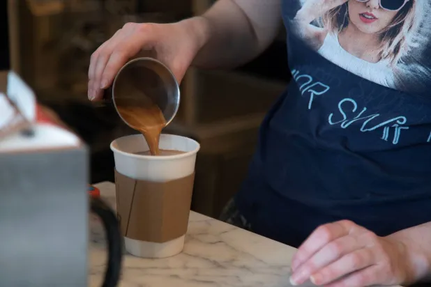 إحدى العاملات في مقهى كندي تصب القهوة للزبون (أرشيفية - أ.ف.ب)