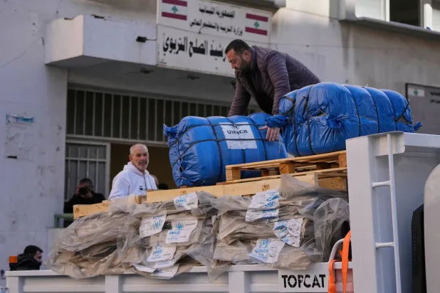 رجل يقوم بتفريغ مساعدات إنسانية مقدمة من المفوضية السامية للأمم المتحدة لشؤون اللاجئين بمدرسة في بيروت تستخدم مأوى للأشخاص الذين نزحوا بسبب الحرب... 9 مارس 2026 (أ.ب)