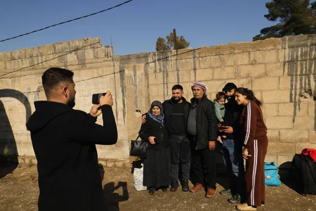 صورة تذكارية قبل عودة العائلات النازحة من عفرين في القامشلي مع انطلاق أول قافلة تقل نحو 400 عائلة تحت إشراف وفد من الحكومة السورية يوم 9 مارس 2026 (أ.ف.ب)