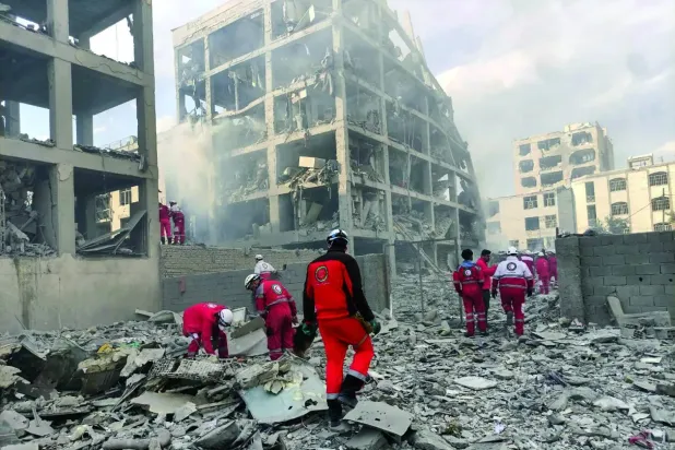 Dün başkent Tahran'daki Rasalat Meydanı'nda ABD-İsrail hava saldırısı sonucu hasar gören bölgede arama kurtarma çalışması yapan acil müdahale ekipleri (DPA)