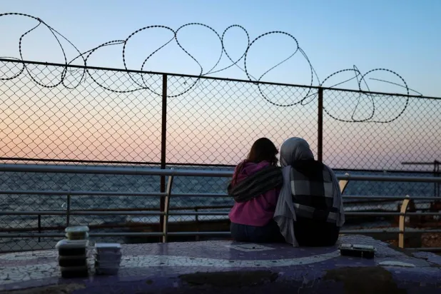 Two women look at the sea as boxes of food prepared for Iftar during Ramadan lie on a bench along the Corniche, following an escalation between Hezbollah and Israel amid the US-Israeli conflict with Iran, in Beirut, Lebanon, March 10, 2026. (Reuters)