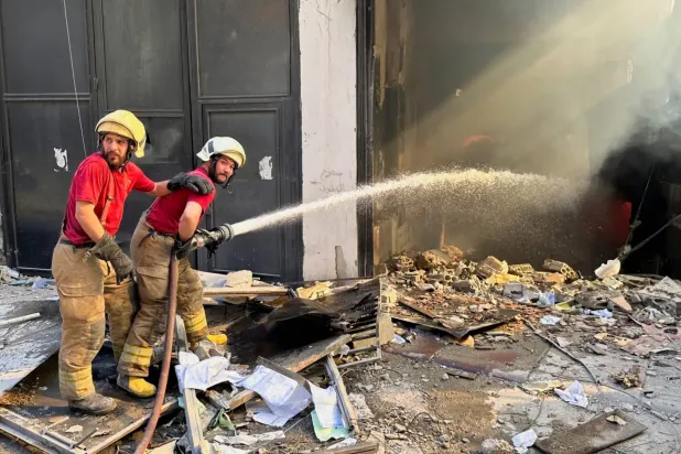 Sivil savunma ekipleri, Beyrut’un güney banliyölerinde İsrail’in hedef aldığı bir binada çıkan yangını söndürmeye çalışıyor. (Reuters)