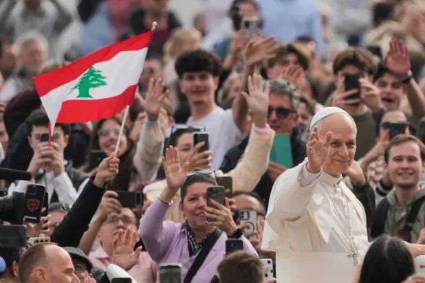 البابا ليو بابا الفاتيكان يلوّح للحضور وأحدهم يحمل عَلم لبنان (أ.ب)