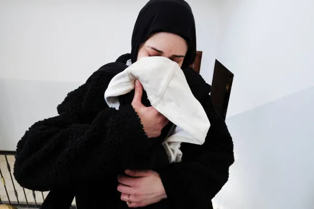 ملك بعيرات تشم رائحة زوجها ثائر حمايل على السترة التي تركها قبل مقتله خلال هجوم شنه مستوطنون إسرائيليون على الفلسطينيين (رويترز)