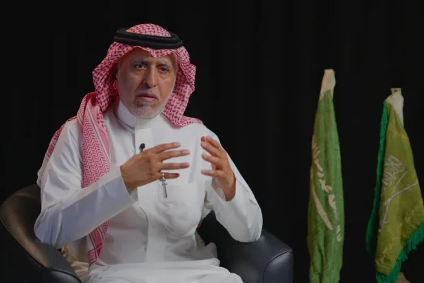 Saudi researcher Adnan Al-Tarif poses with two Saudi state flags (Asharq Al-Awsat)