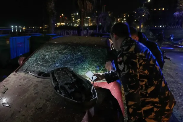 Beyrut'un Ramlet el-Bayda bölgesinde İsrail hava saldırısında hasar gören aracı inceleyen bir güvenlik görevlisi (AP)