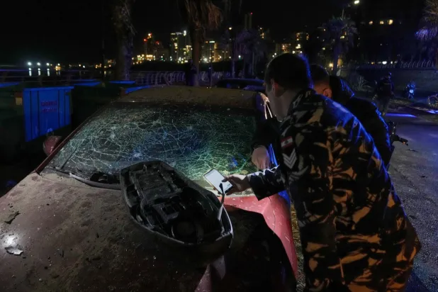 Police officers inspect a damaged car hit in an Israeli airstrike at the Ramlet al-Baida public beach in Beirut, Lebanon, early Thursday, March 12, 2026. (AP Photo/Bilal Hussein)