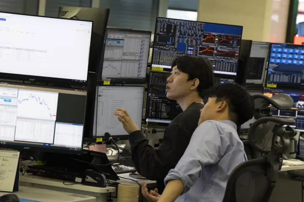 متداولون كوريون جنوبيون يعملون أمام شاشات تعرض مؤشرات الأسهم في بنك هانا في سيول (إ.ب.أ)