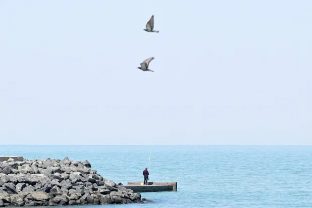 A man fishes in the Gulf waters off Kuwait City on March 10, 2026. (Photo by YASSER AL-ZAYYAT / AFP) 