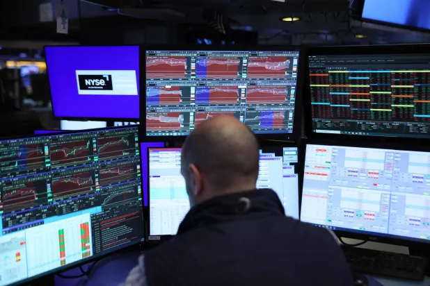 متداول يراقب شاشات تعرض مؤشرات الأسهم في بورصة نيويورك (أ.ف.ب)