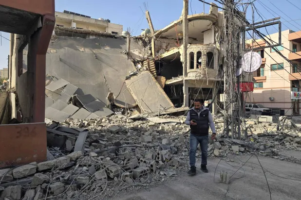 A man stands by the rubble of a destroyed building in the aftermath of overnight Israeli airstrikes in the southern Lebanese coastal city of Tyre on March 12, 2026. (Photo by Kawnat HAJU / AFP)