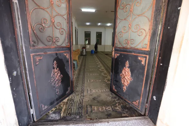 فلسطيني ينظف داخل المسجد في دوما (إ.ب.أ)