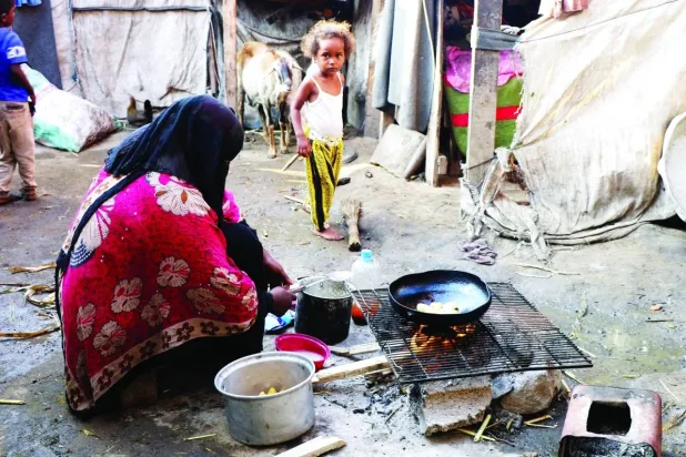 يمنية نازحة تعدّ وجبة فقيرة متواضعة لأطفالها (رويترز)