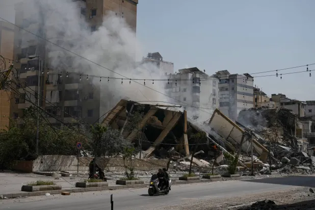 رجل على دراجة نارية يَعبر أمام بناء مدمَّر في ضاحية بيروت الجنوبية (أ.ب)