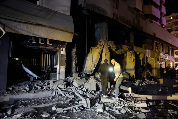 People stand amid debris in front of damaged buildings in the aftermath of a reported Israeli strike in Zuqaq al-Blat, central Beirut, Lebanon March 12, 2026. REUTERS/Mohamed Azakir