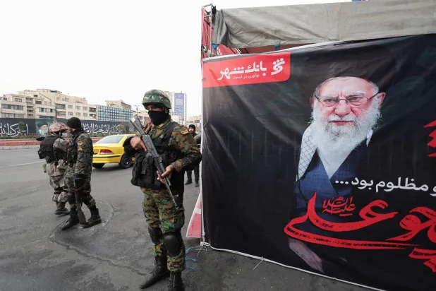 أفراد من الشرطة يقفون حراساً في أحد شوارع العاصمة الإيرانية طهران بجوار لافتة كبيرة تحمل صورة المرشد الإيراني الراحل علي خامنئي... 12 مارس 2026 (رويترز)
