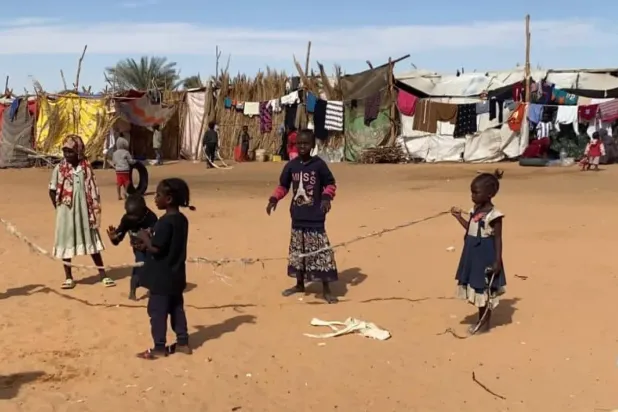 أطفال يلعبون أمام خيام للنازحين السودانيين على أطراف مدينة الكفرة الليبية (الصفحة الرسمية لبلدية المدينة)