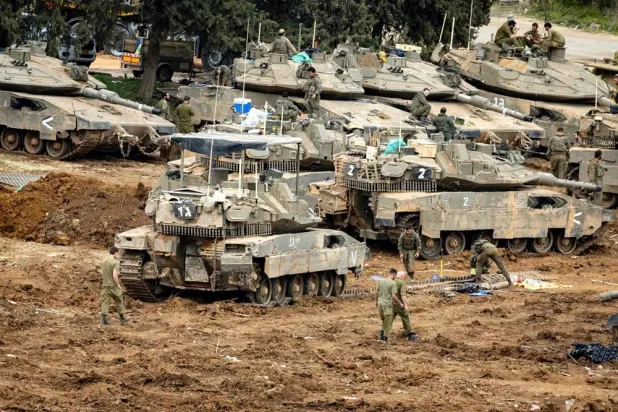 Israeli soldiers work on the belts for their tanks at a staging area in the Upper Galilee in northern Israel near the border with Lebanon on March 13, 2026. (AFP) 