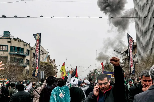  الدخان يتصاعد من موقع ضربة إسرائيلية في طهران بينما يحيي إيرانيون «يوم القدس» أمس (أ.ف.ب)