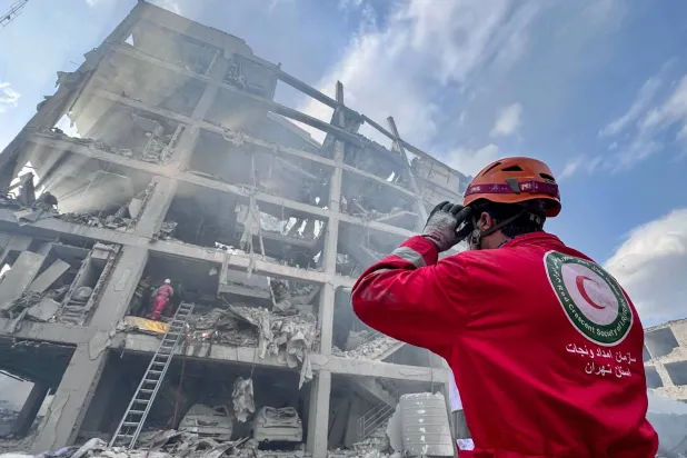 FILED - 10 March 2026, Iran, Tehran: A member of the Iranian Red Crescent Society (IRCS) rescue teams works at the site of a building damaged in a US-Israeli airstrike in Resalat Square. Photo: -/ZUMA Press Wire/dpa