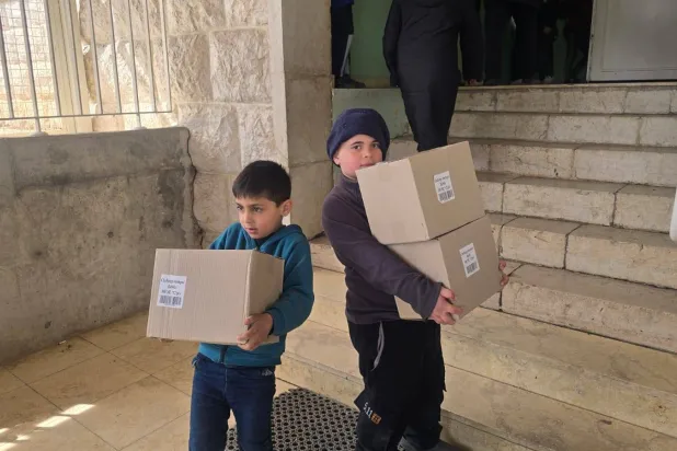 طفلان يحملان مساعدات غذائية في مركز إيواء للنازحين بزحلة شرق لبنان (الشرق الأوسط)