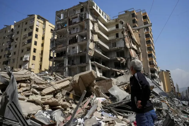 لبناني يسير قرب ركام مبانٍ دمرتها غارات إسرائيلية في ضاحية بيروت الجنوبية الشهر الحالي (رويترز)