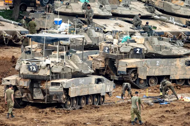 Israeli soldiers work on the belts for their tanks at a staging area in the Upper Galilee in northern Israel near the border with Lebanon on March 13, 2026.  (Photo by Odd ANDERSEN / AFP) / 