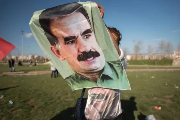 شاب كردي يرفع ثورة لزعيم «حزب العمال الكردستاني» عبد الله أوجلان خلال تجمع في تركيا للمطالبة بإطلاق سراحه (رويترز)