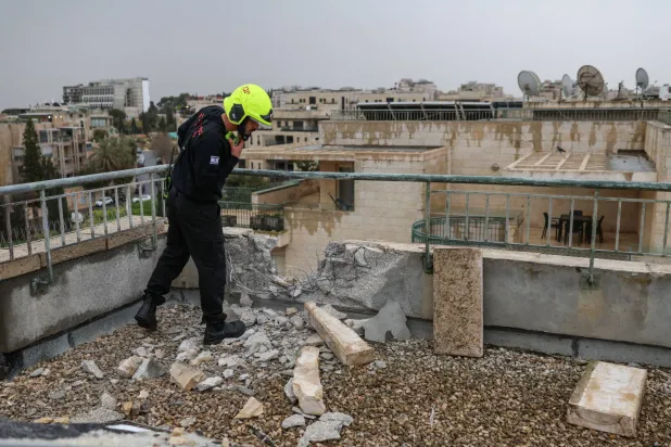 رجل إنقاذ يعاين أضراراً على سطح مبنى سكني في القدس عقب هجوم صاروخي إيراني السبت (رويترز)