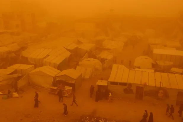  Palestinians walk amid a sandstorm in a tent camp sheltering Palestinians displaced during the two-year Israeli offensive, in Khan Younis in the southern Gaza Strip, March 14, 2026. (Reuters)