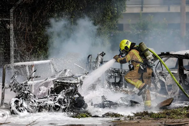 رجل إطفاء يُخمد حريقاً اندلع في سيارة إثر اصطدام قذيفة بها جراء غارة إيرانية جنوب تل أبيب (أ.ف.ب)