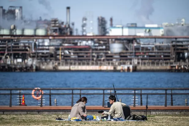 رجل يعزف على الغيتار في حديقة هيغاشي-أوغيشيما هيغاشي في منطقة كيهين الصناعية، في خليج طوكيو والتي تضم عمليات تكرير النفط (أ.لف.ب)