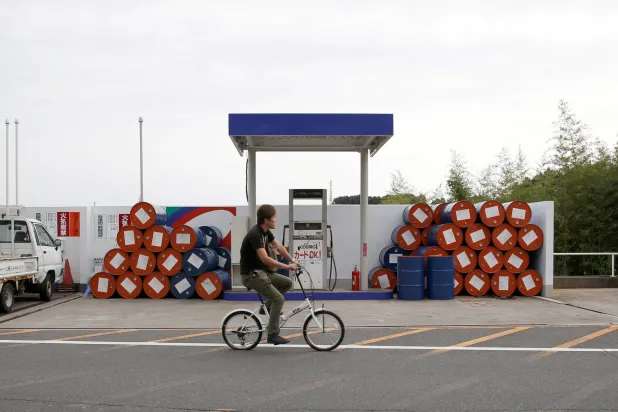 رجل يمر بدراجته الهوائية أمام محطة وقود في مدينة سوزوكا، اليابان (رويتزر)