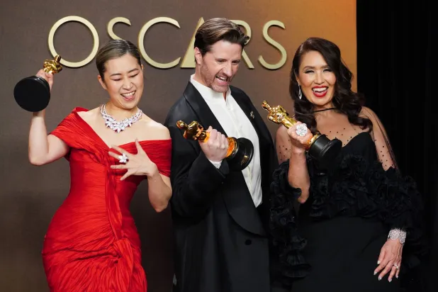 Maggie Kang, from left, Chris Appelhans, and Michelle L.M. Wong, winners of the award for animated feature film for "K-pop Demon Hunters," pose in the press room at the Oscars on Sunday, March 15, 2026, at the Dolby Theatre in Los Angeles. (Photo by Jordan Strauss/Invision/AP)