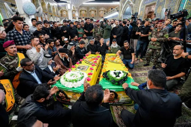 Mourners pray by the caskets of two slain fighters from Iraq's Hezbollah Brigades (Kataeb Hezbollah), who were killed in a strike on their site in Baghdad's al-Jadriya area, during their funeral at the shrine of Imam Ali in Iraq's central holy city of Najaf on March 14, 2026. (Photo by Qassem al-KAABI / AFP)