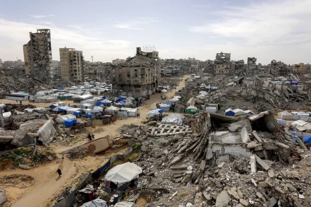 خيام تؤوي فلسطينيين نازحين إلى جانب مبانٍ مدمرة في مدينة غزة (أ.ف.ب)