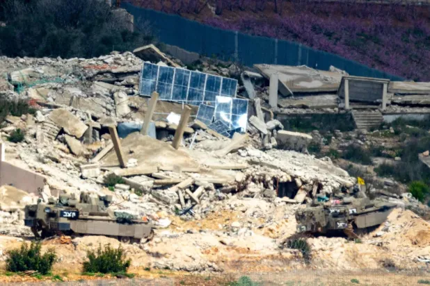 İsrail savaş araçları dün Lübnan'ın güneyindeki harap olmuş bir köyden geçiyor (AFP)