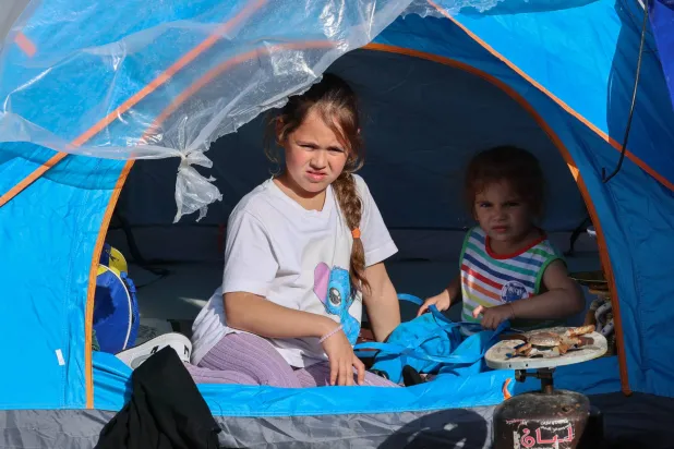 طفلان يلوذان إلى خيمة تأوي النازحين من الضاحية الجنوبية في وسط بيروت (إ.ب.أ)