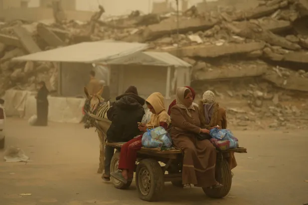 فلسطينيون يركبون عربة يجرها حمار وسط عاصفة رملية في مدينة غزة (أ.ب)