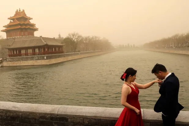 FILE PHOTO: A couple react during their wedding photoshoot near the Forbidden City, as the city is hit by sandstorm, in Beijing, China March 15, 2021. REUTERS/Tingshu Wang/File Photo