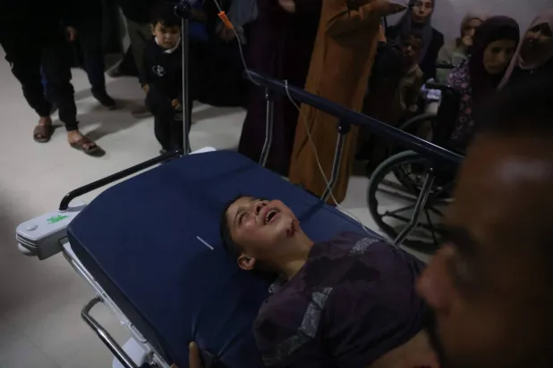 رجل يهرع حاملاً طفلاً يُقال إنه أصيب في غارة إسرائيلية إلى مستشفى ناصر بخان يونس الثلاثاء (أ.ب)