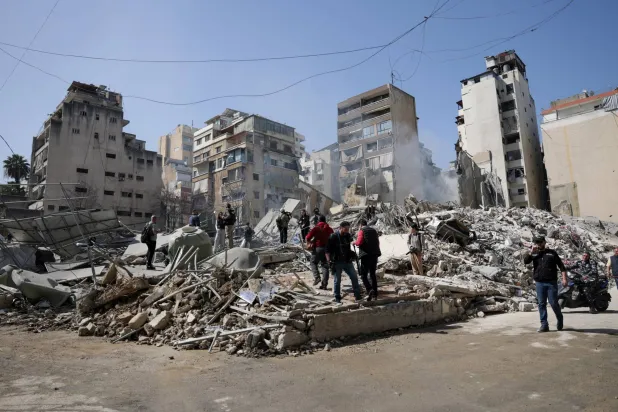  People walk amidst debris at the site of an Israeli strike, following an escalation between Hezbollah and Israel amid the US-Israeli conflict with Iran, Zuqaq al-Blat district in central Beirut, Lebanon, March 18, 2026. (Reuters)