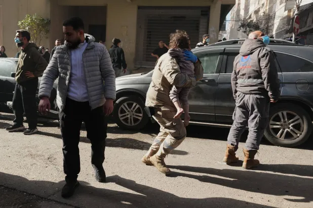 A rescue worker carries a child at the scene of an Israeli airstrike in central Beirut, Lebanon, Wednesday, March 18, 2026. (AP Photo/Hassan Ammar)
