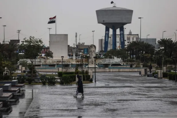 An Iraqi man walks through Al-Umma Park during rainfall in Baghdad on March 15, 2026. (AFP)