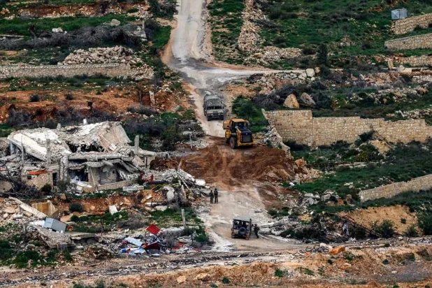 Israeli soldiers and a bulldozer conduct an operation in a southern Lebanese village along the border, as seen from a position in the Upper Galilee in northern Israel on March 18, 2026. (AFP)